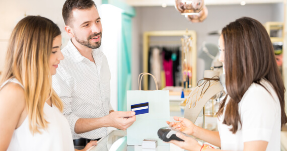 Jeune couple dans une boutique paye avec une carte de crédit