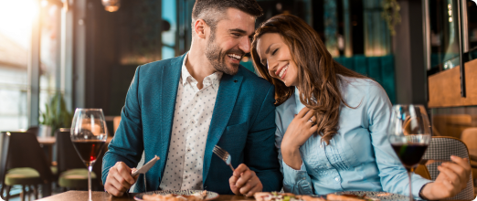 Photo d’un couple en tenue professionnelle mangeant dans un restaurant chic avec un verre de vin